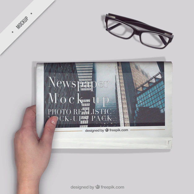 Free PSD | Person reading a newspaper with a glasses on the desktop