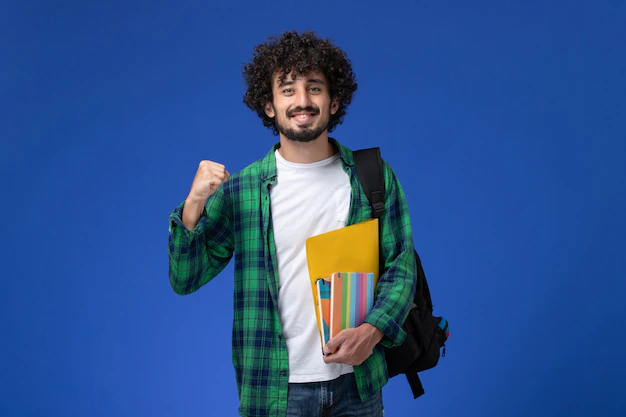 Free Photo | Front view of male student wearing black backpack holding copybooks and files on blue wall