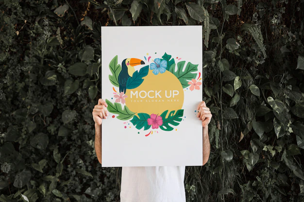 Free PSD | Man presenting poster mockup in front of leaves
