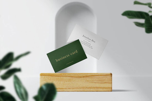 Free PSD | Clean minimal business card mockup floating on wooden plate with leaves