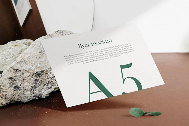 Free PSD | Clean minimal a5 flyer mockup floating on top wood background with leaves. psd file.