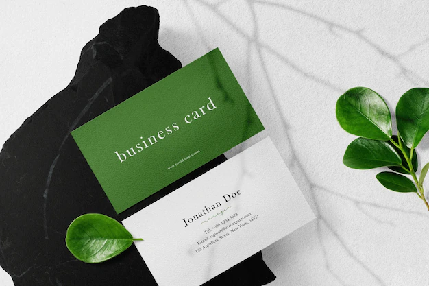 Free PSD | Clean minimal business card mockup on black stone with leaves