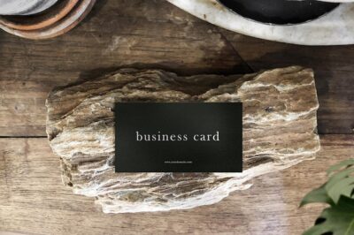 Free PSD | Clean minimal business card mockup on table with rock and plant foreground