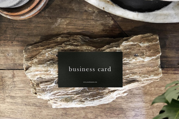 Free PSD | Clean minimal business card mockup on table with rock and plant foreground