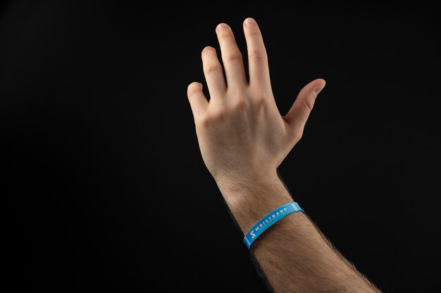 Free PSD | Realistic hand wearing blue bracelet with dark background