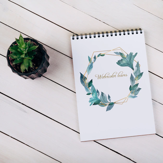Free PSD | Spring notebook mockup with decorative plant in top view