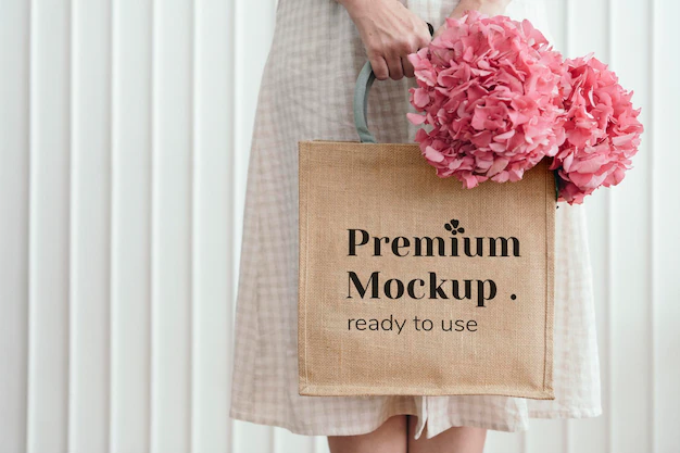 Free PSD | Woman holding a woven tote bag mockup with pink hydrangea flowers