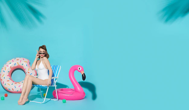 Free Photo | Happy woman chilling in lounge chair near flamingo rubber ring on blue copy space background