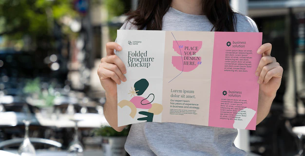 Free PSD | Woman holding trifold brochure mock-up with abstract shapes