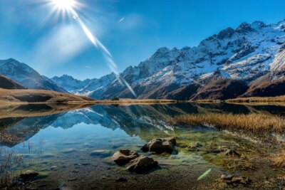 Free Photo | Beautiful shot of a crystal clear lake next to a snowy mountain base during a sunny day
