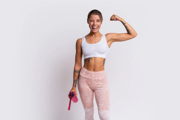 Free Photo | Fit blond woman with perfect smile in stylish sportswear looking at camera and holding bottle of water over white wall. demonstrate muscles.