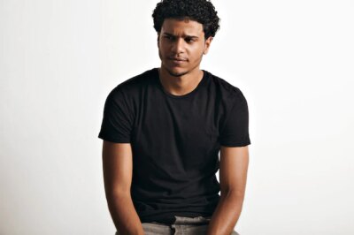 Free Photo | Ironic thoughtful handsome young man with an afro wearing a black sleeveless cotton t-shirt on white wall