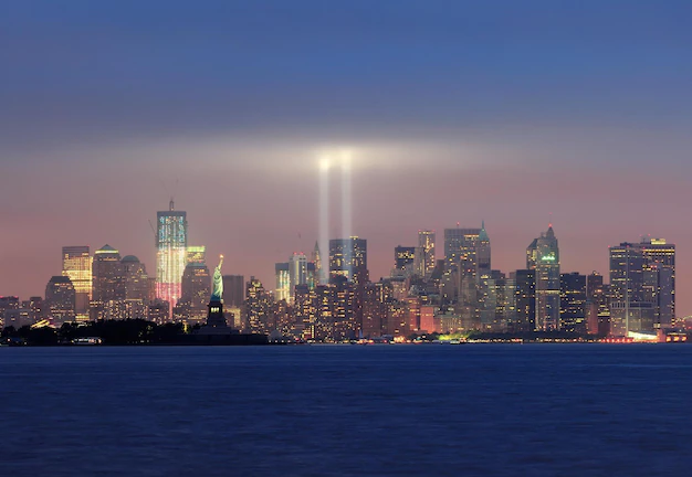 Free Photo | New york city manhattan downtown skyline panorama at night with statue of liberty and light beams in memory of september 11 viewed from new jersey waterfront.