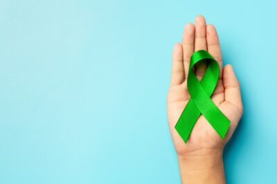Free Photo | World mental health day. green ribbon put in human's hand on blue background