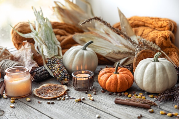 Free Photo | Cozy autumnal composition with candles, pumpkins, corn on a wooden surface in a rustic style.