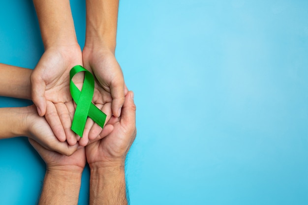 Free Photo | World mental health day. green ribbon put in human's hands on blue background