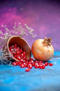 Free Photo | Bottom view pomegranate seeds in a bowl a pomegranate on purple free place