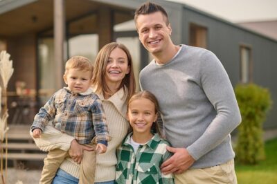Free Photo | Happy people.. young beautiful woman with little boy attractive man and long-haired school-age girl in casual clothes hugging joyful looking at camera standing near house
