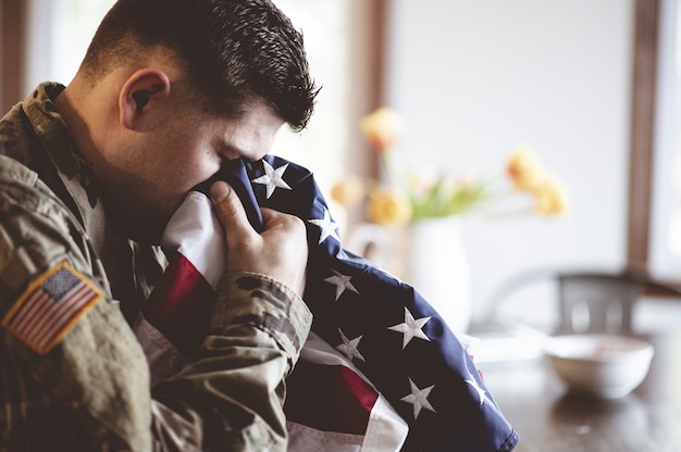 Free Photo | American soldier mourning and praying with the american flag in his hands